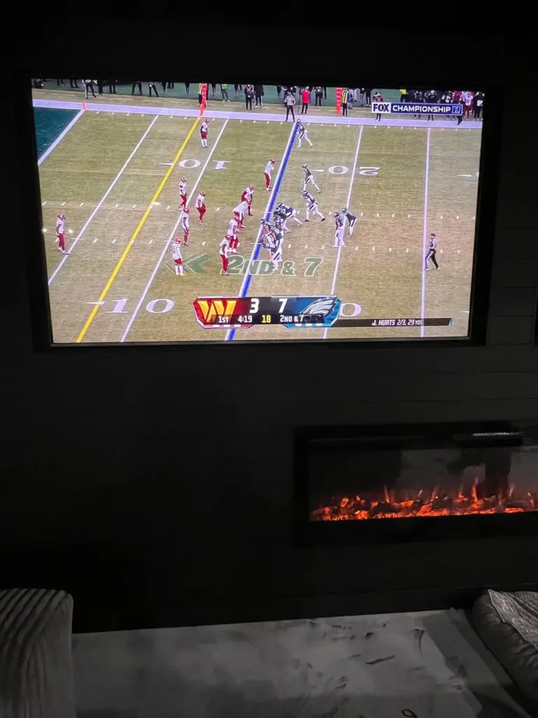 Wall-mounted TV installation in an Indianapolis home theater, showcasing a seamless entertainment setup with a built-in electric fireplace.